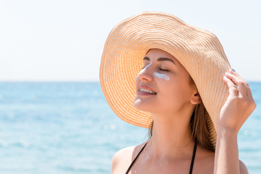 woman on the beach wearing a sun hat and sunscreen